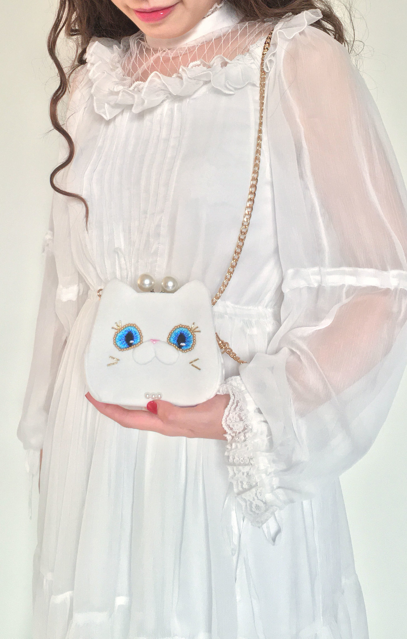 穿白色蕾絲連衣裙的捲髮女人左手捧著白貓夫人短夾錢包