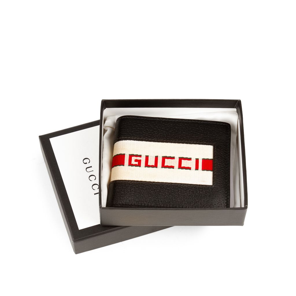 A GUCCI wallet in embossed leather GG with web stripe in…