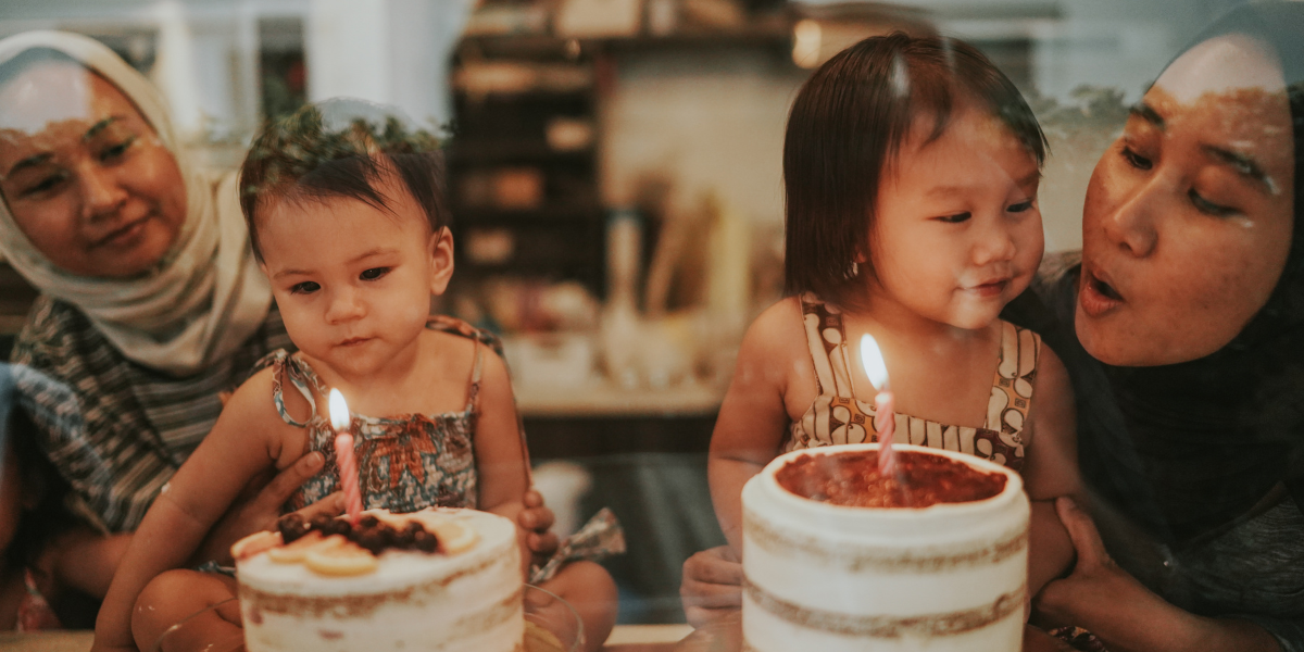 mothers blowing out birthday cake together with daughters