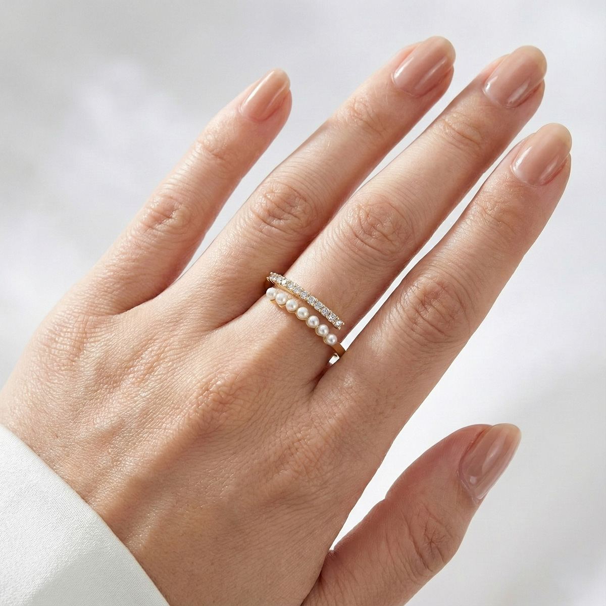 柔光小珍珠層疊戒指配戴於手指上,細緻珍珠排列與簡約金色戒圈設計,呈現溫柔優雅的日常氣質