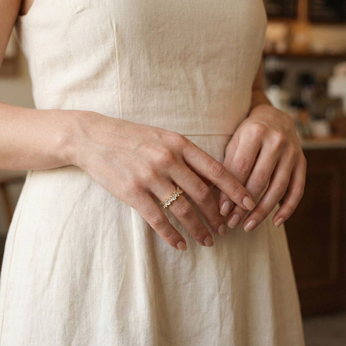 真人配戴金色爪鑲水鑽戒指,梯形切割水鑽設計,搭配淺色洋裝呈現溫柔優雅的日常穿搭風格