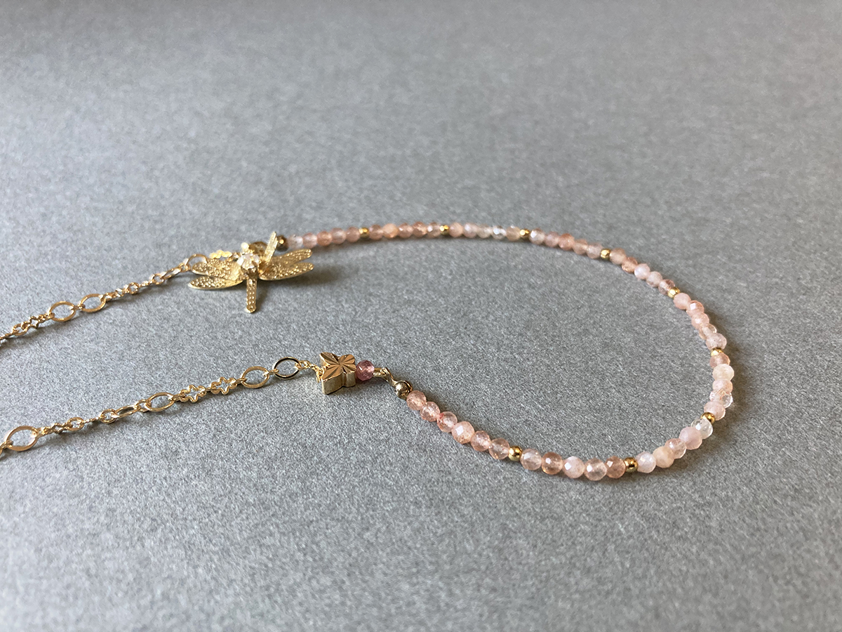太陽石蜻蜓點水項鍊平放細節圖，橙粉色太陽石水晶珠鍊搭配金色延長鍊與蜻蜓吊飾