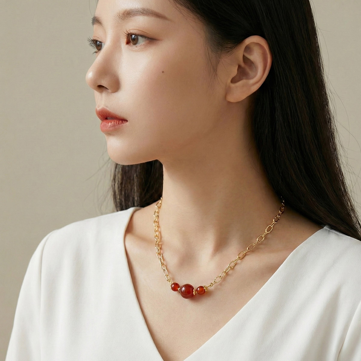 真人女性側臉配戴暖紅瑪瑙玉髓項鍊,金色鍊條搭配紅色圓珠,呈現自然優雅的日常穿搭比例