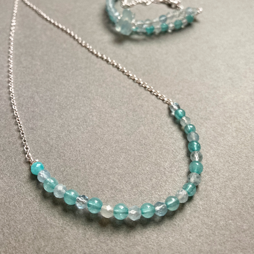 冰藍玉髓與藍磷石漸層水晶項鍊細節，圓珠切面在灰色背景下呈現清透藍白層次與自然光澤