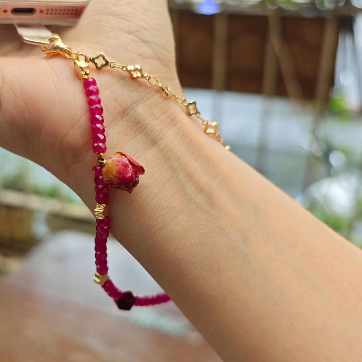 天然紅剛石玫瑰手機掛繩配戴示意，紅剛石切面珠與乾燥玫瑰設計呈現實際使用比例