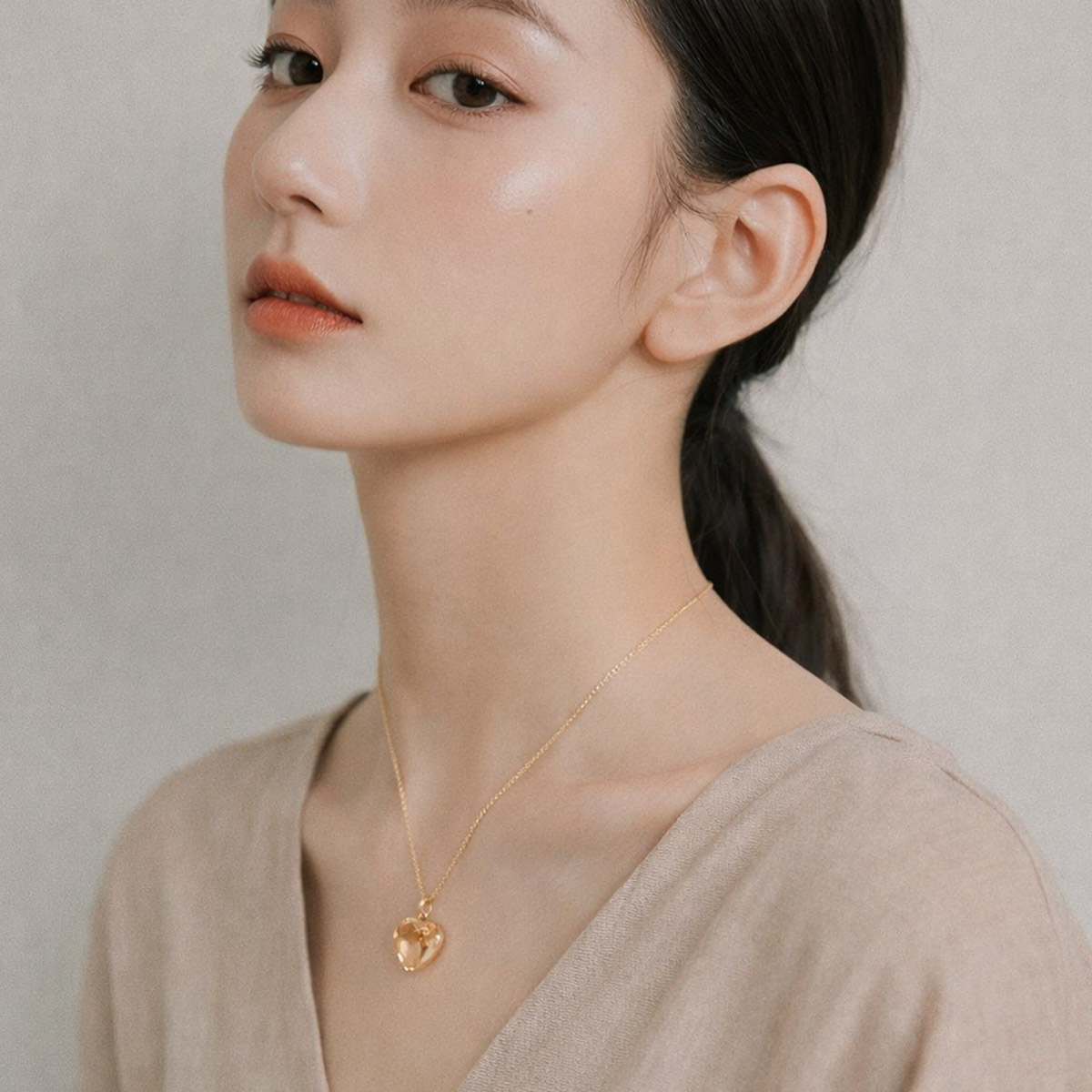 女性配戴鈦晶心型項鍊情境照,金色鍊條自然垂墜於鎖骨中央,心形鈦晶呈現柔和金黃光感,適合日常佩戴