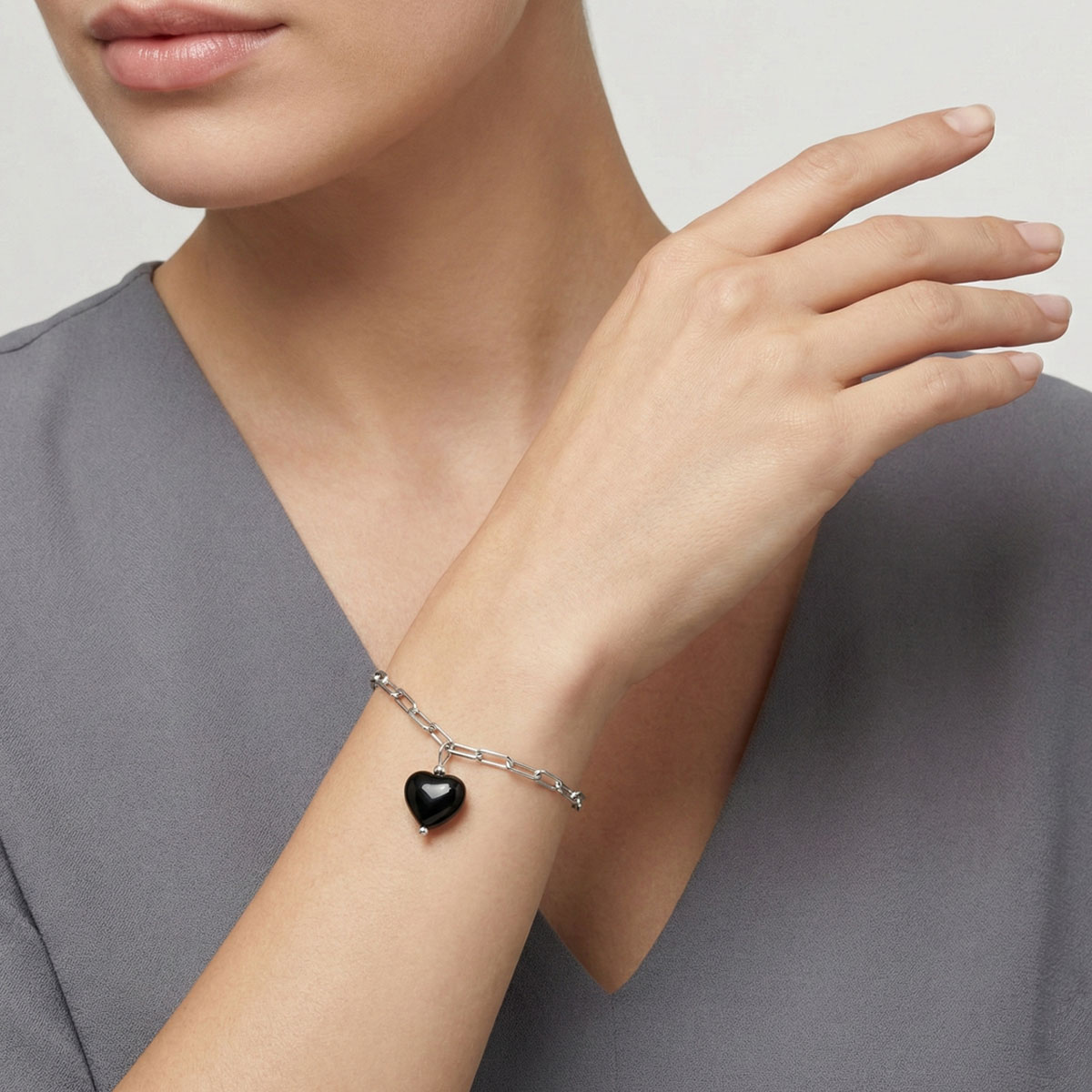 模特兒手腕配戴黑曜石心型純銀手鍊,亮面黑曜石愛心墜飾自然垂墜,呈現日常穿搭中的實際佩戴比例