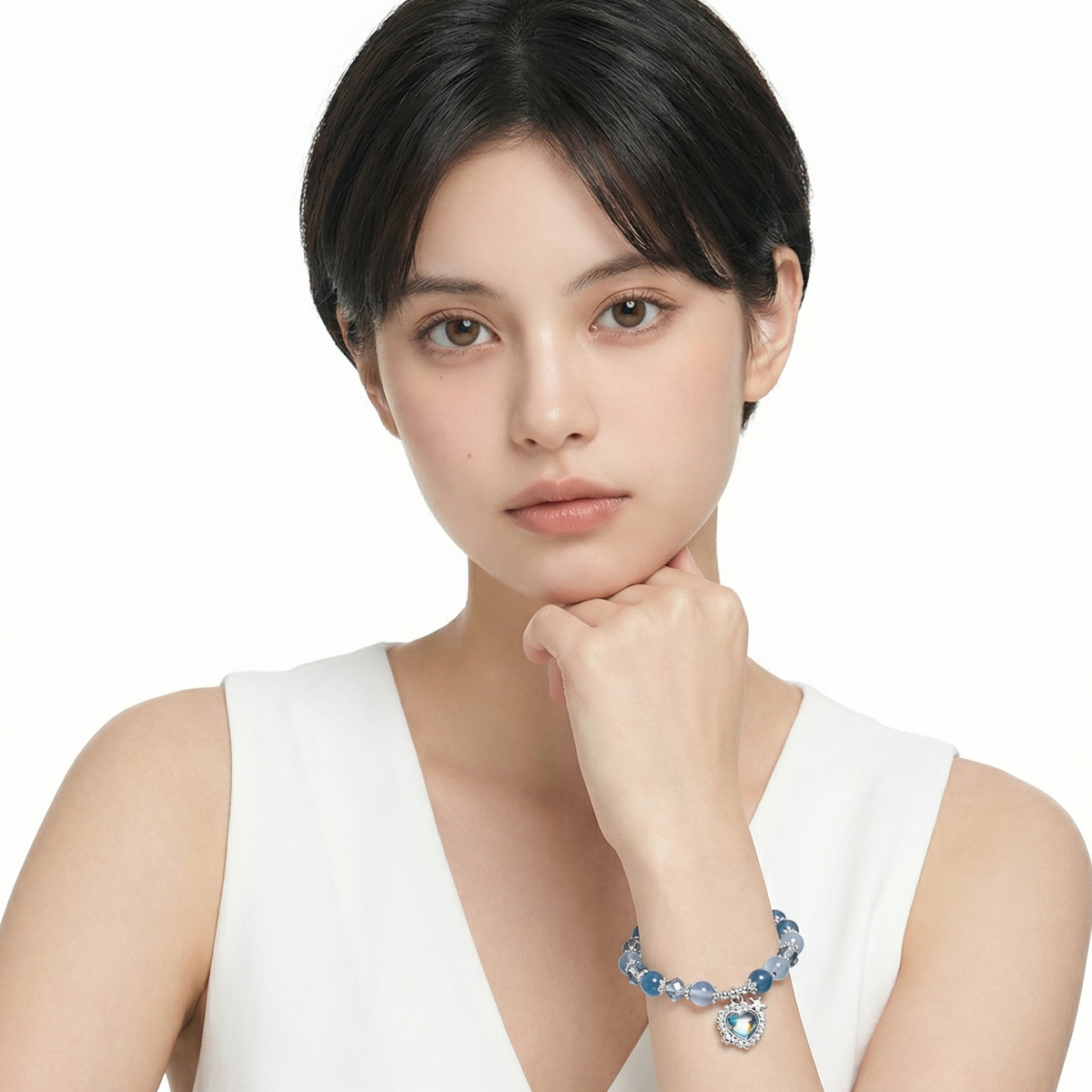 女性模特兒手腕配戴海洋藍糖心瑪瑙水晶手鍊，藍色瑪瑙圓珠與透明切面水晶搭配銀色愛心吊飾，自然光下的日常配戴示意