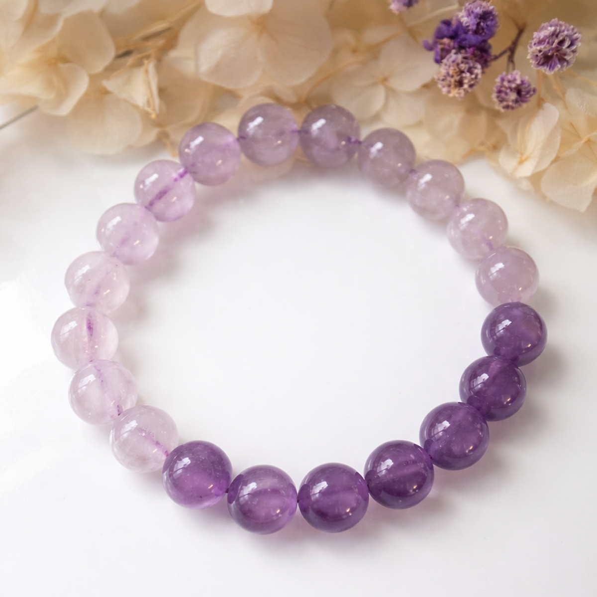 晨曦紫韻漸層紫水晶手鍊,搭配柔和花材背景,展現紫水晶由淺至深的色澤層次與溫柔氣質