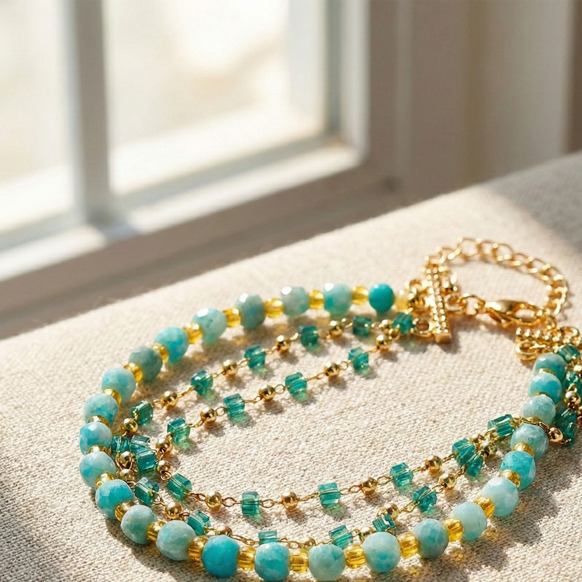 天河石多層次星河手鍊置於窗邊自然光下,藍綠色天河石與金色鍊條在柔和光線中展現溫潤層次,呈現清新日常質感