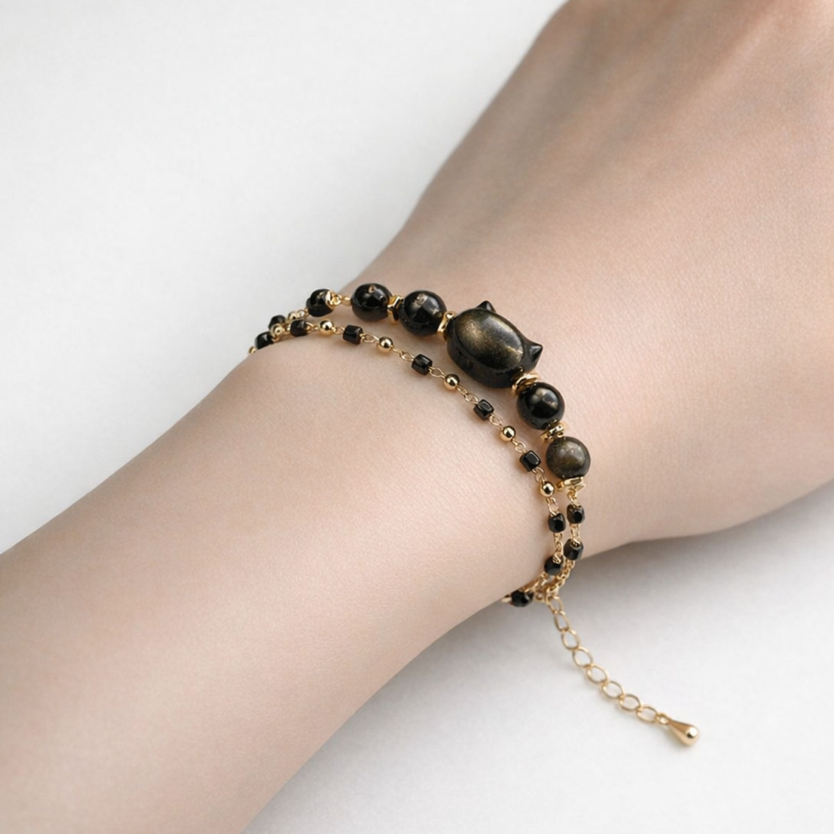 黑金曜石貓咪雙層設計手鍊實際配戴於手腕，展現黑曜石光澤與低調金色細節的日常風格