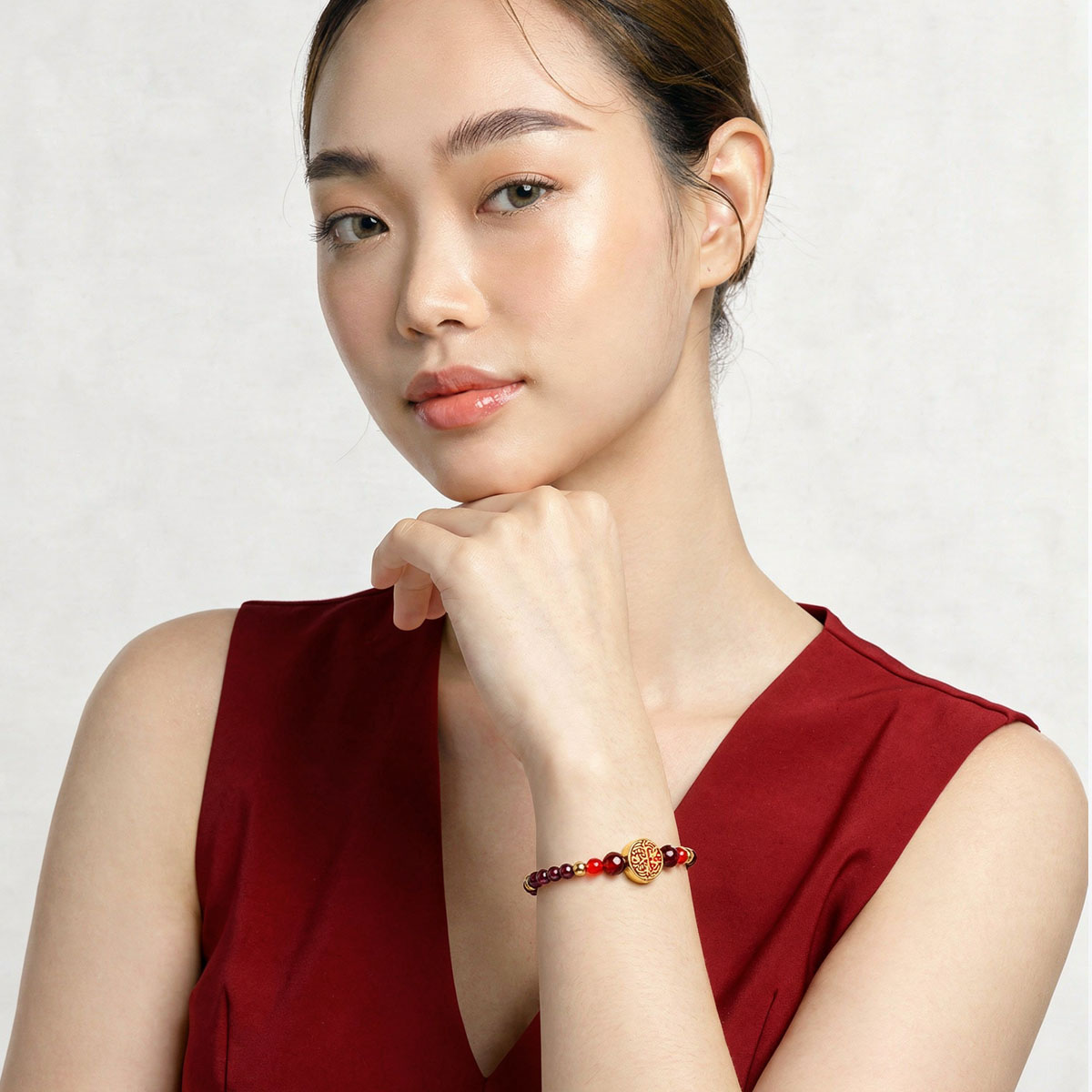 女性半身肖像配戴紅石榴石達摩不倒翁手鍊,酒紅色石榴石珠串搭配金色達摩吊飾,呈現優雅日常穿搭風格