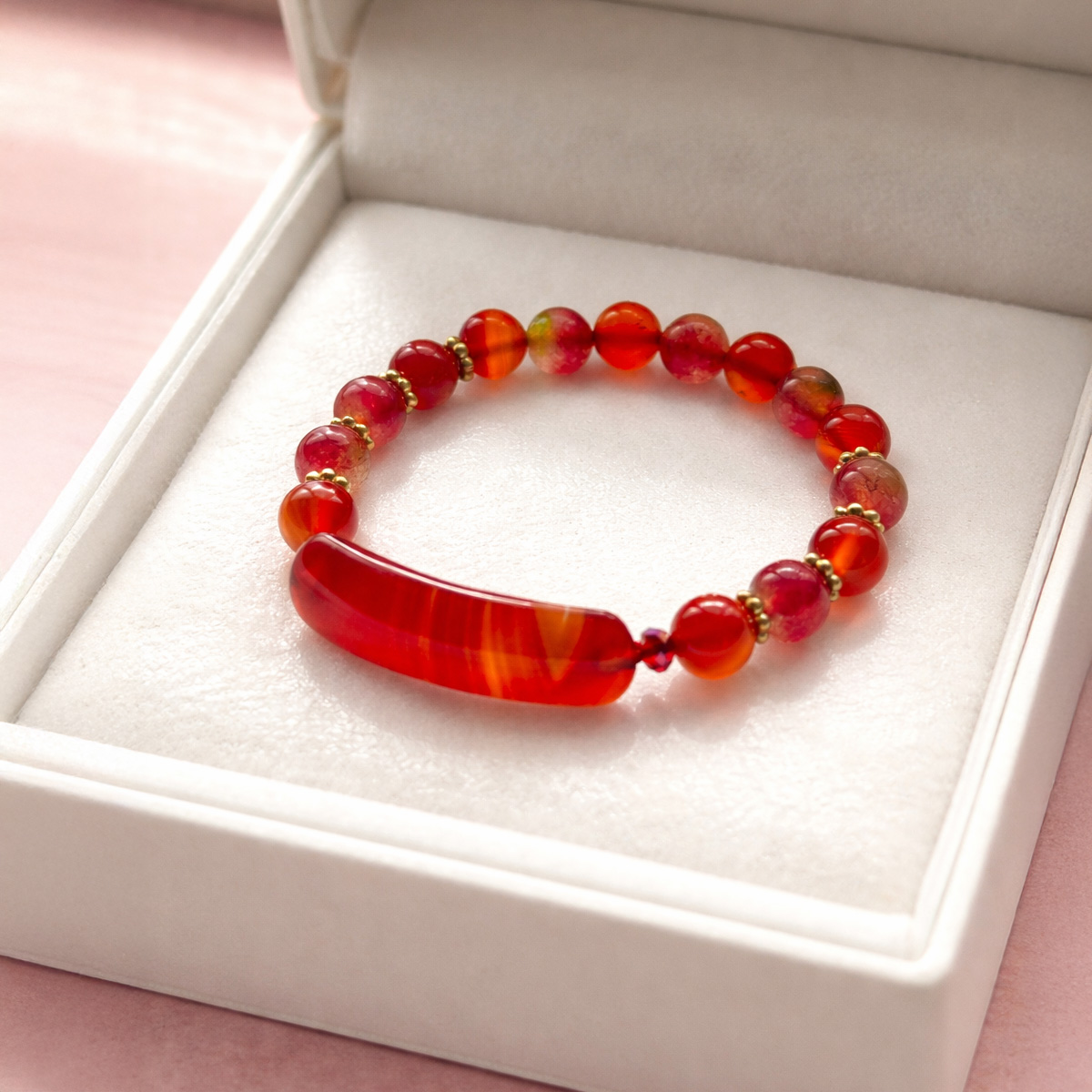 紅瑪瑙西瓜碧璽手鍊置於白色首飾盒中,呈現溫潤紅色珠光與長形紅瑪瑙主石設計