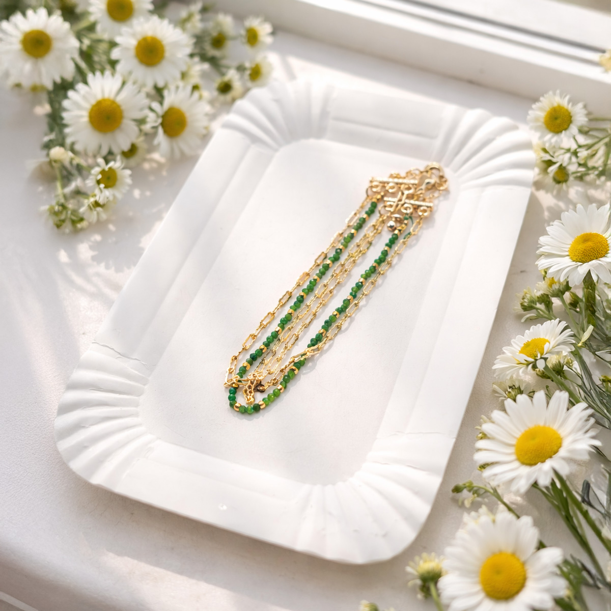 綠碧璽金質極細鍊手鍊置於白色托盤,窗邊自然光與小雛菊營造清新柔和氛圍