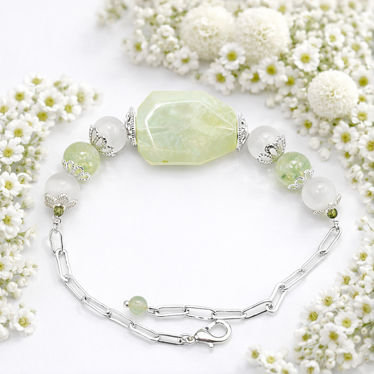 橄欖石白貓眼石手鍊花材情境拍攝，搭配白色小花營造清新療癒氛圍